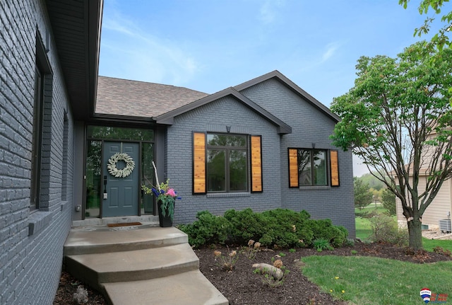 view of front of house with brick siding and roof with shingles