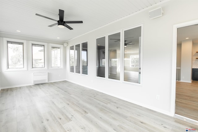 unfurnished sunroom with radiator heating unit and ceiling fan