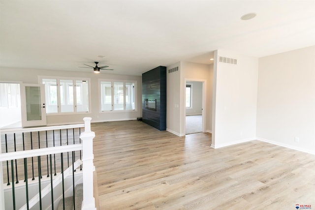 unfurnished living room featuring a ceiling fan, visible vents, light wood finished floors, and baseboards