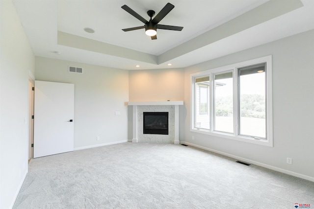 unfurnished living room with visible vents, a raised ceiling, and a fireplace