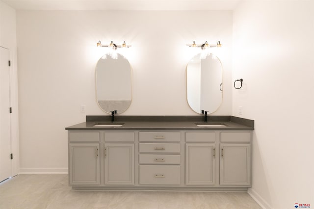 bathroom with double vanity, baseboards, and a sink