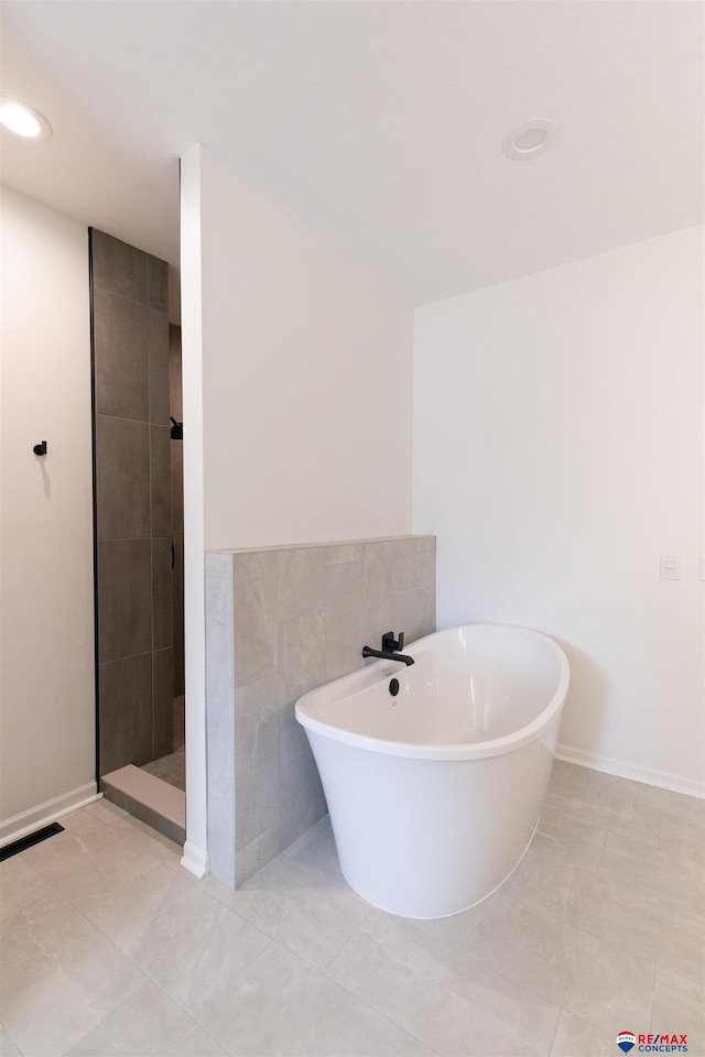 full bath featuring tile patterned floors, a freestanding tub, recessed lighting, tile walls, and tiled shower