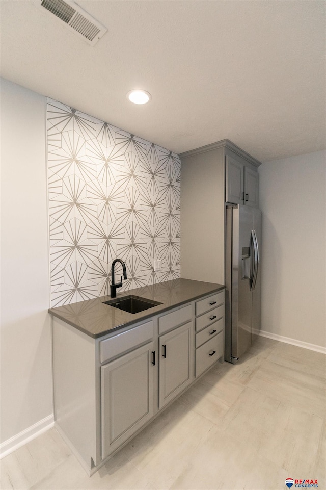 kitchen featuring a sink, visible vents, dark countertops, and stainless steel fridge with ice dispenser