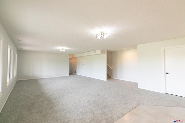 carpeted empty room with stairs and baseboards