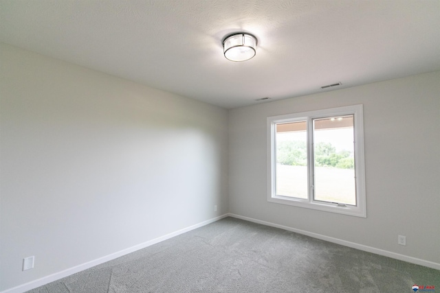 carpeted spare room with visible vents and baseboards