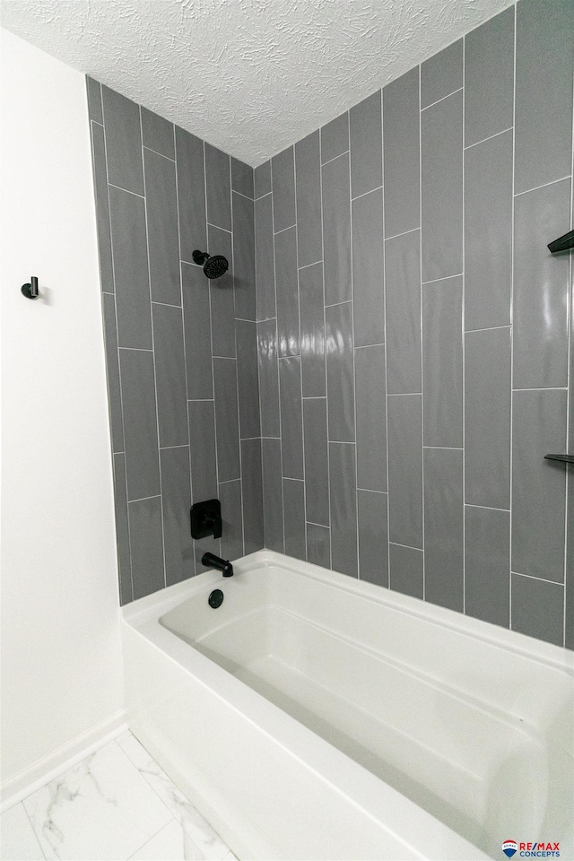 bathroom featuring marble finish floor, tub / shower combination, a textured ceiling, and baseboards