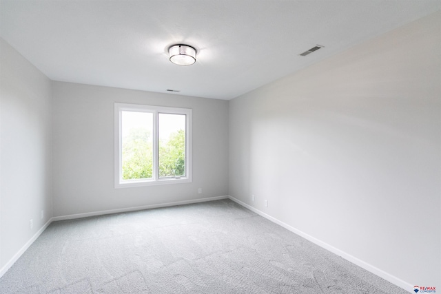 carpeted spare room featuring visible vents and baseboards