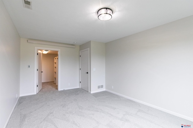 empty room featuring visible vents, baseboards, and light colored carpet