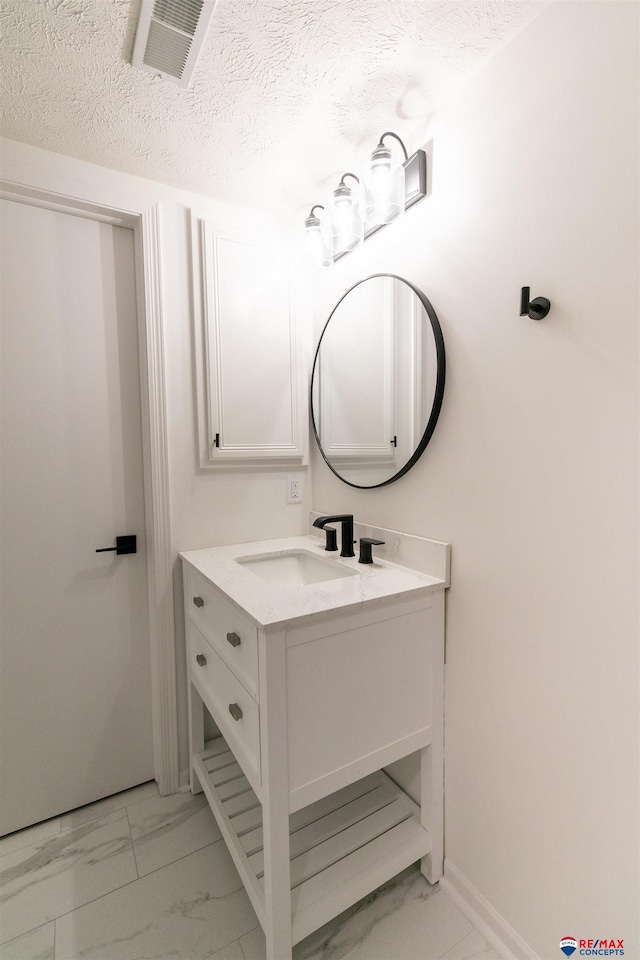 bathroom featuring visible vents, marble finish floor, a textured ceiling, baseboards, and vanity