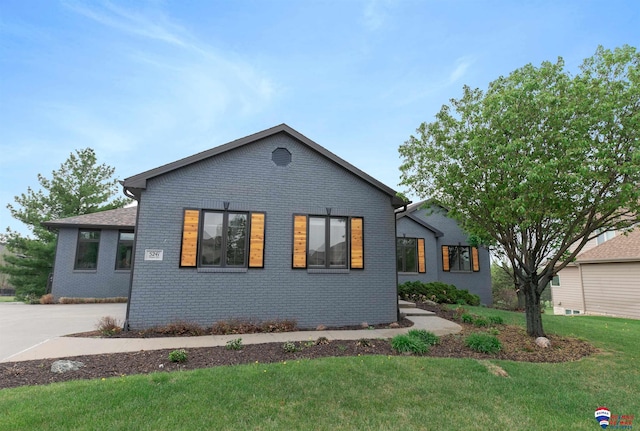 view of front of home with brick siding, concrete driveway, and a front yard