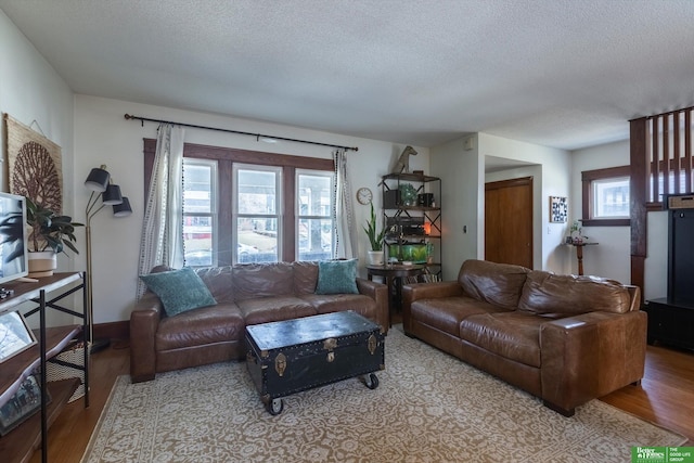 living room featuring a wealth of natural light, a textured ceiling, and wood finished floors