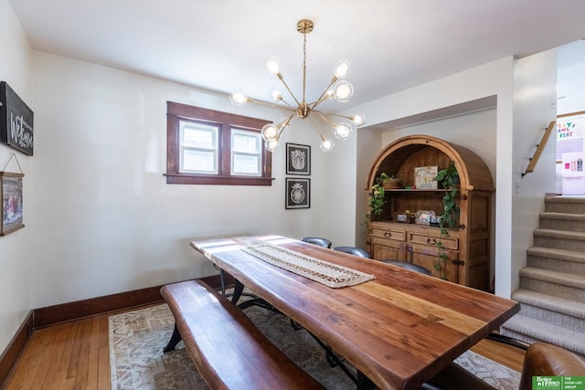 dining space with stairway, baseboards, an inviting chandelier, and wood finished floors