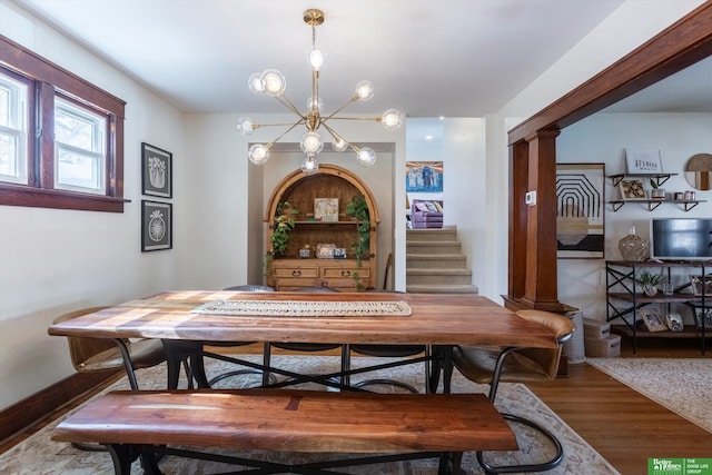 dining room featuring a notable chandelier, wood finished floors, and stairs