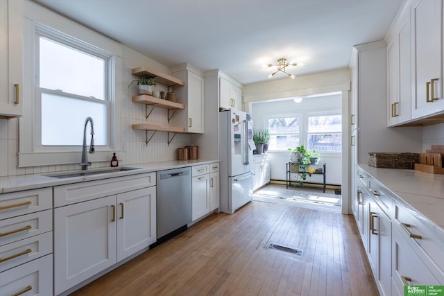 kitchen featuring white cabinetry, a sink, white fridge with ice dispenser, stainless steel dishwasher, and backsplash