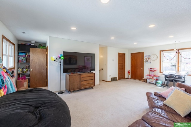 living area featuring recessed lighting, visible vents, and light carpet