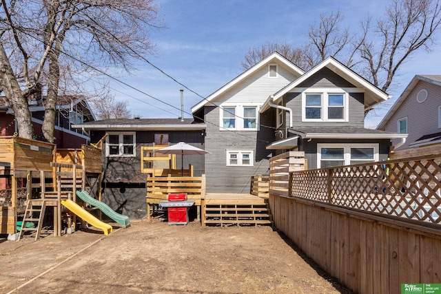 back of house featuring a wooden deck and a playground