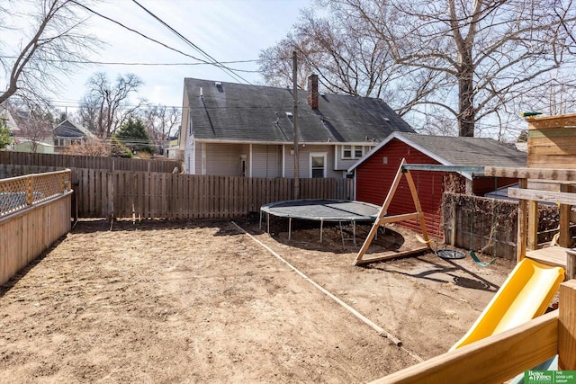 view of yard with a fenced backyard, an outdoor structure, and a trampoline