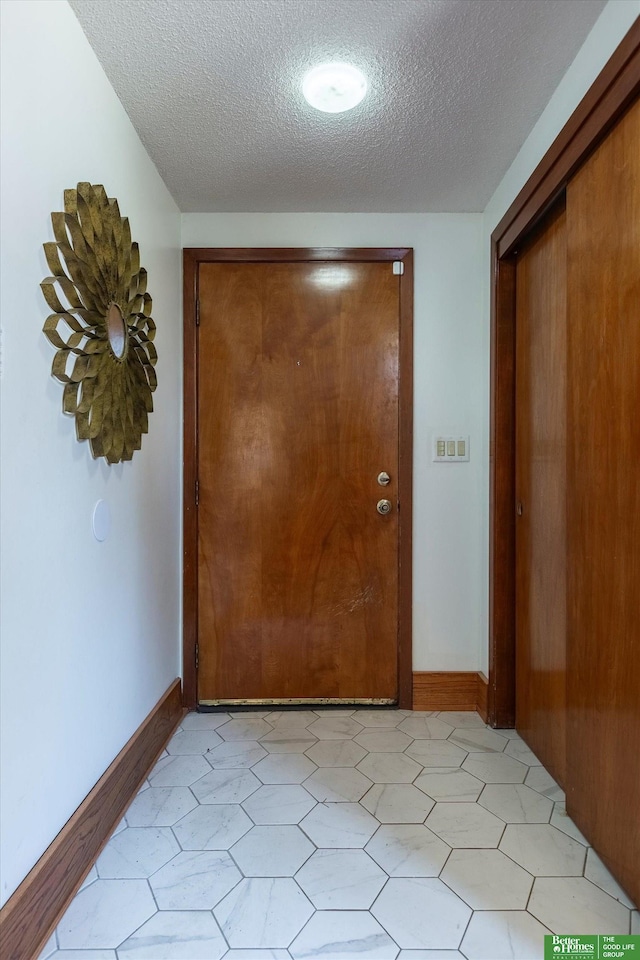 hallway featuring baseboards and a textured ceiling