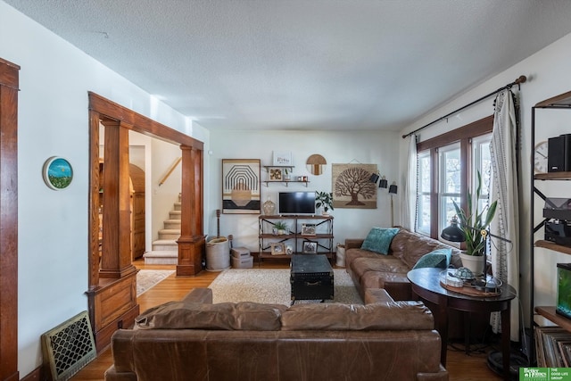 living area featuring stairway, a textured ceiling, and wood finished floors