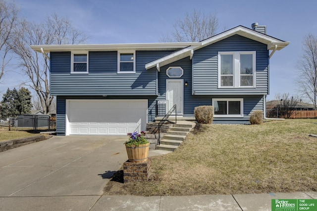 raised ranch with a front yard, concrete driveway, fence, and a garage