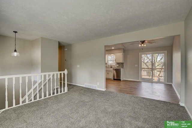 unfurnished room featuring visible vents, baseboards, a ceiling fan, and dark colored carpet