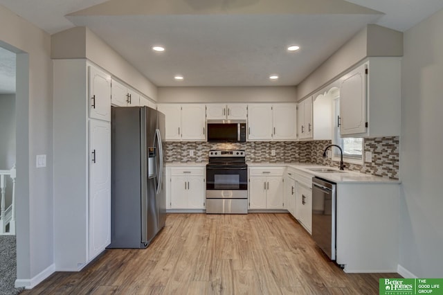 kitchen featuring a sink, tasteful backsplash, stainless steel appliances, light wood-style floors, and light countertops