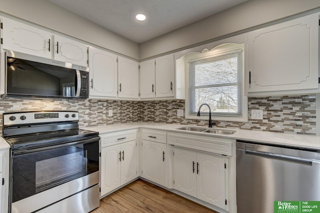 kitchen with appliances with stainless steel finishes, light countertops, and a sink