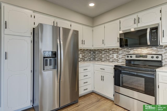 kitchen with stainless steel appliances, light countertops, light wood-style floors, white cabinetry, and tasteful backsplash