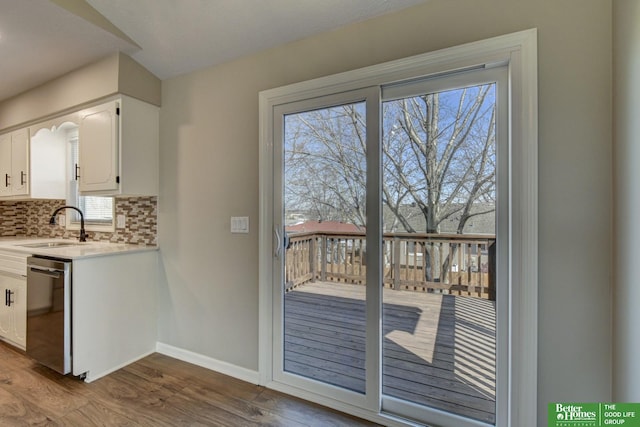 kitchen with a sink, wood finished floors, white cabinets, decorative backsplash, and dishwasher