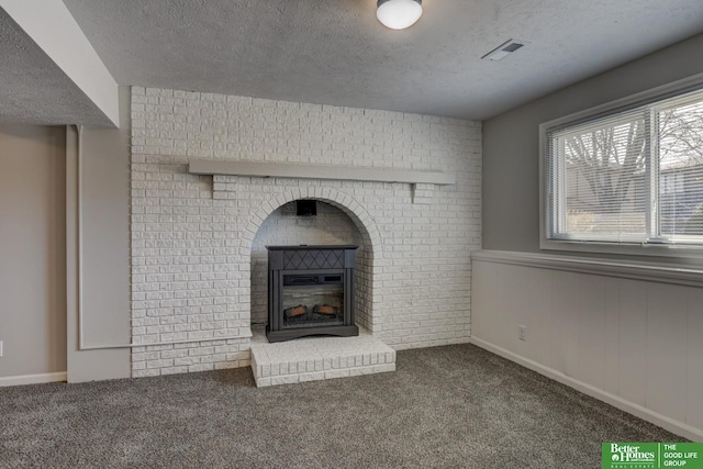 unfurnished living room featuring visible vents, carpet floors, a textured ceiling, and a fireplace