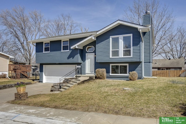 split foyer home featuring fence, a front yard, a chimney, a garage, and driveway