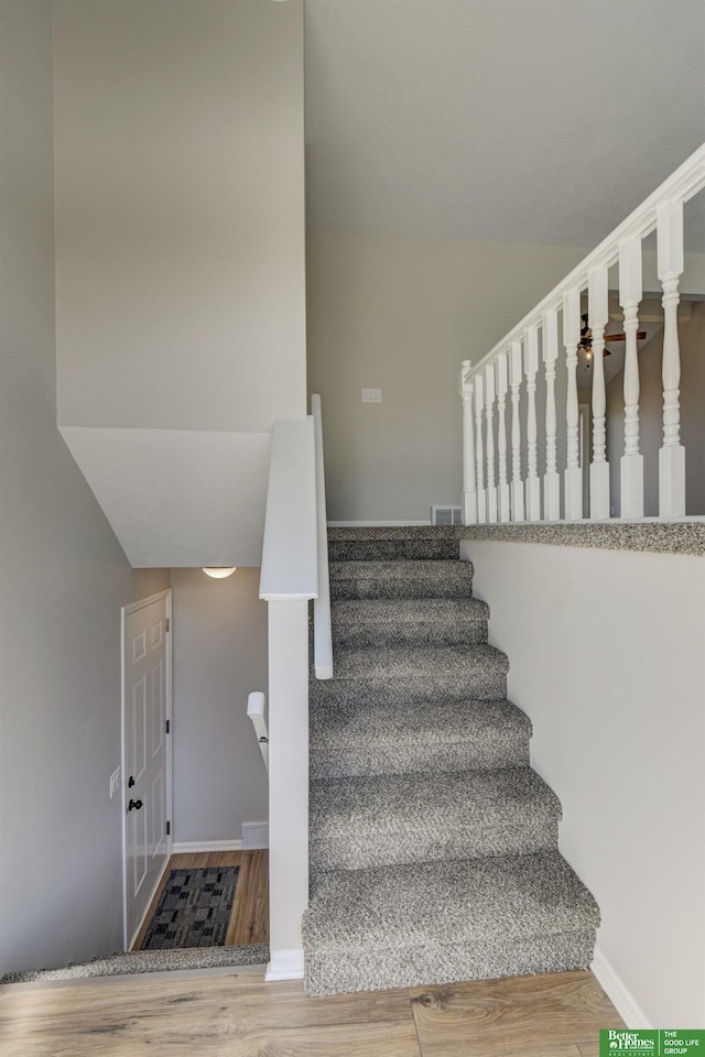 stairs with visible vents, baseboards, and wood finished floors