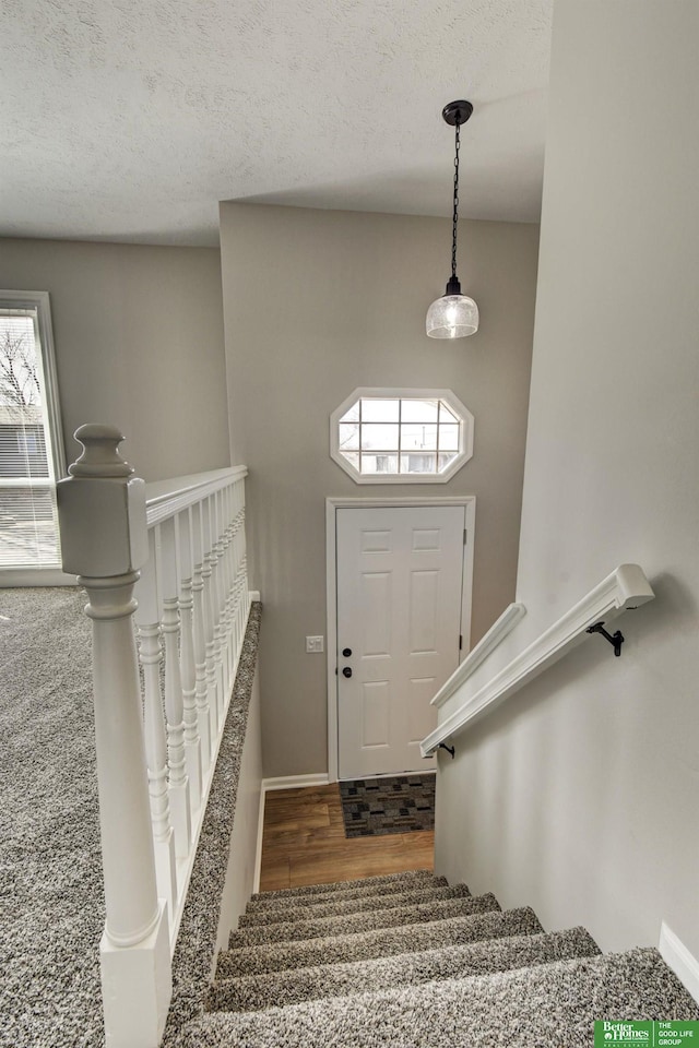 staircase featuring a textured ceiling and wood finished floors