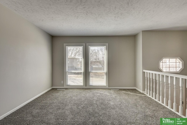 unfurnished room featuring carpet flooring, a textured ceiling, and baseboards