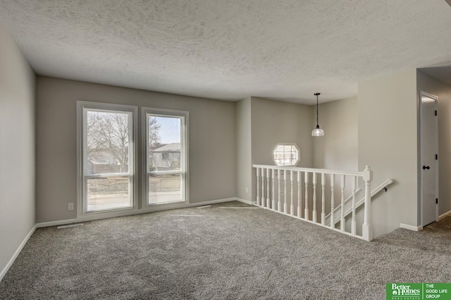 unfurnished room with carpet flooring, a healthy amount of sunlight, baseboards, and a textured ceiling