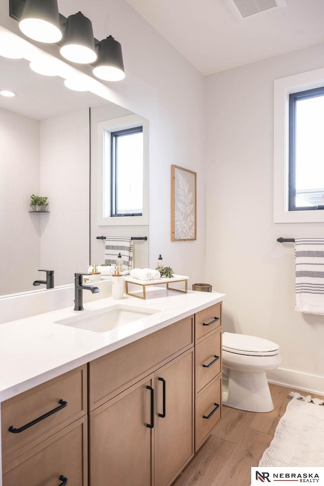 bathroom featuring visible vents, toilet, wood finished floors, and vanity