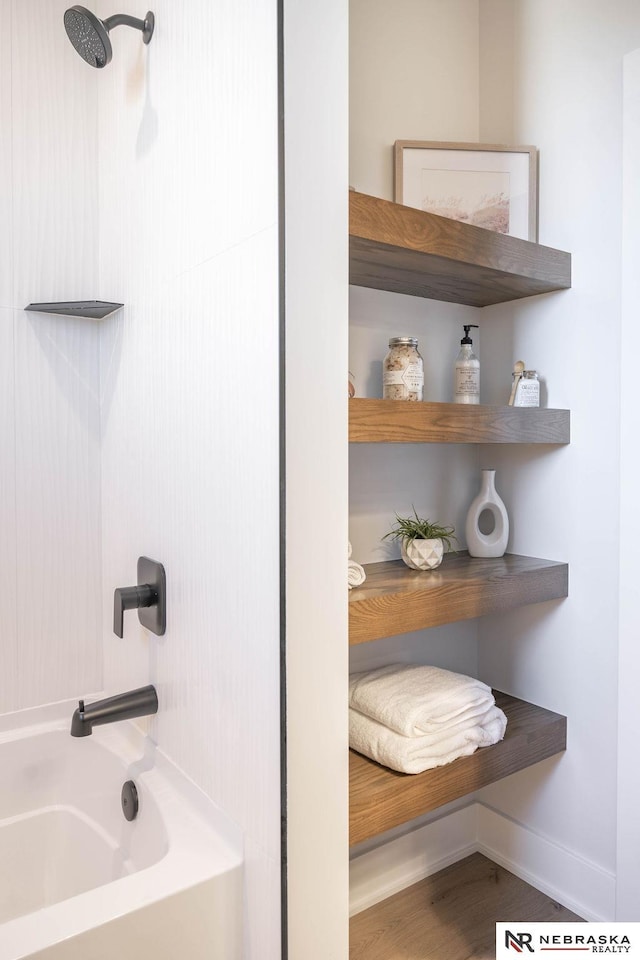 full bath featuring wood finished floors, shower / bath combination, baseboards, and a sink