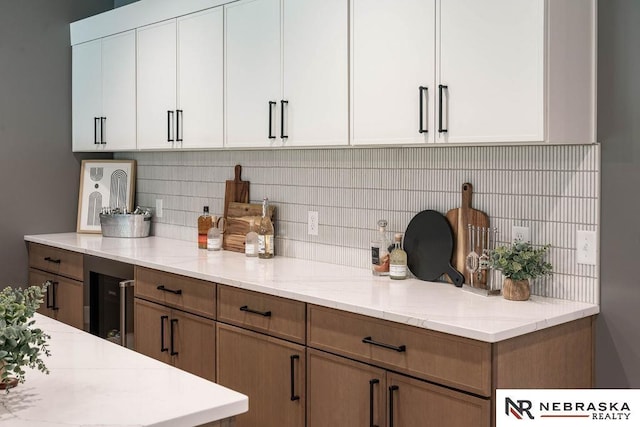 kitchen featuring tasteful backsplash, white cabinets, and light stone counters