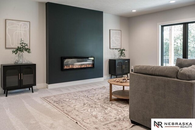 carpeted living room with recessed lighting, baseboards, and a glass covered fireplace