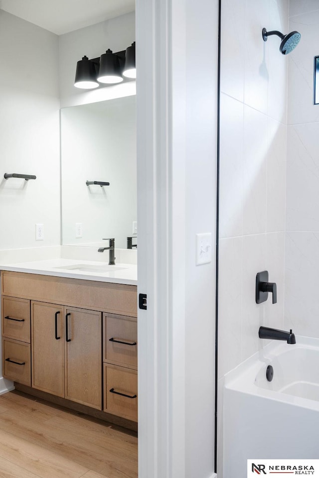 bathroom featuring washtub / shower combination, wood finished floors, and vanity