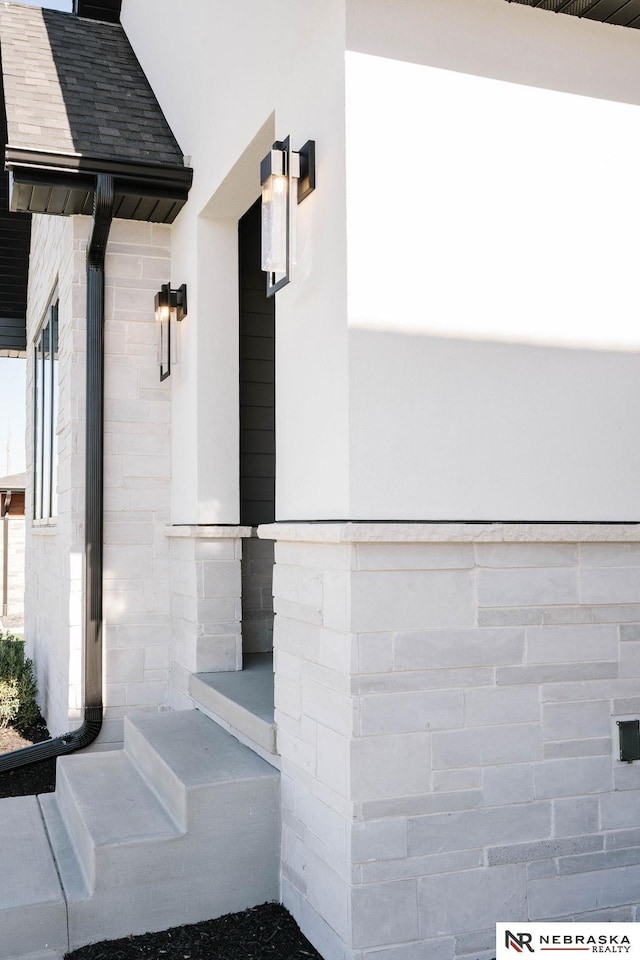 entrance to property with stone siding and roof with shingles