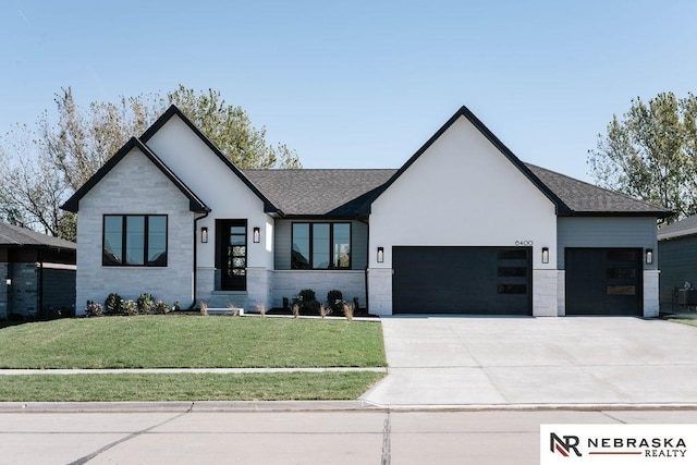 view of front of house with driveway, stone siding, roof with shingles, a front yard, and a garage