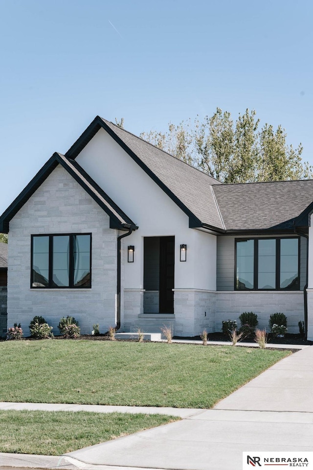 view of front of home featuring stone siding, a shingled roof, and a front yard