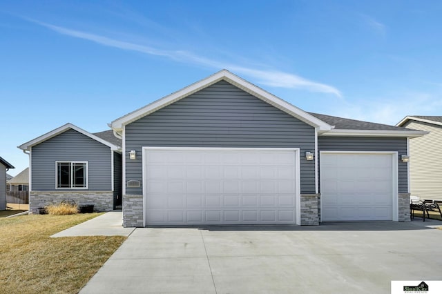 view of front of home featuring stone siding, a front lawn, concrete driveway, and an attached garage