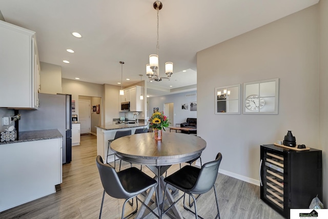 dining area with baseboards, beverage cooler, light wood-type flooring, recessed lighting, and a notable chandelier