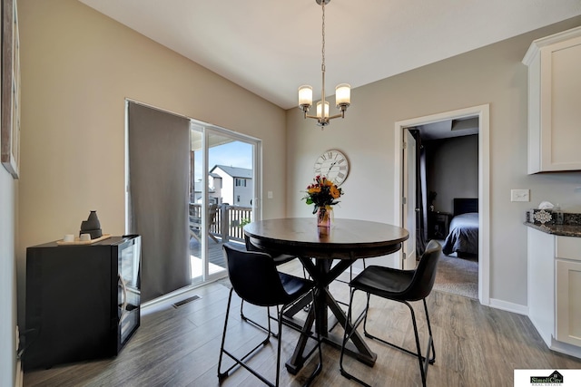 dining area with dark wood-type flooring, baseboards, visible vents, and a chandelier