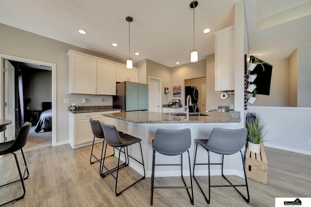 kitchen with a kitchen breakfast bar, light wood-style flooring, freestanding refrigerator, and a sink