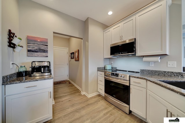 kitchen featuring baseboards, dark stone counters, stainless steel appliances, white cabinetry, and light wood-type flooring