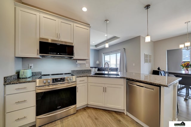 kitchen with a sink, recessed lighting, appliances with stainless steel finishes, a peninsula, and light wood finished floors