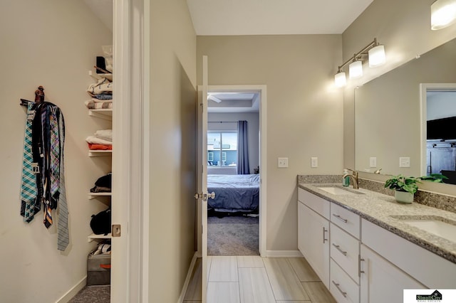 ensuite bathroom featuring double vanity, baseboards, ensuite bathroom, and a sink